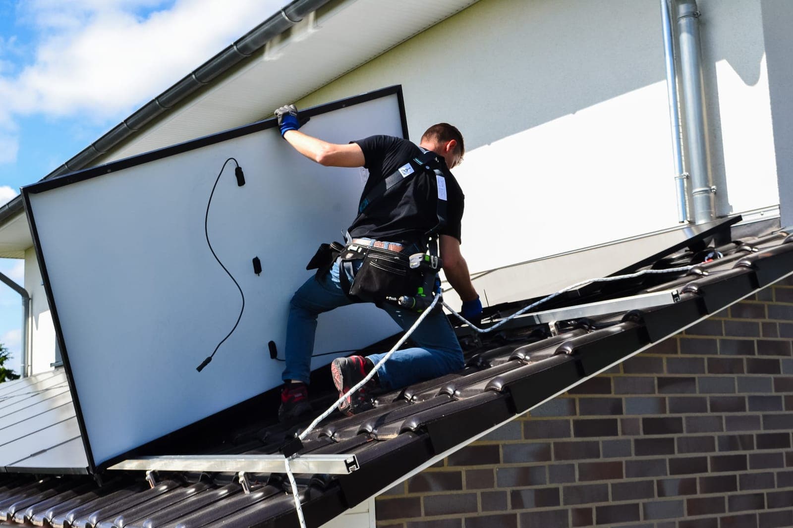 Monteur von Solar Kammer setzt ein Solarmodul auf die Unterkonstruktion eines Satteldachs – Photovoltaik Lüneburg, montiert vom Fachbetrieb aus Vastorf